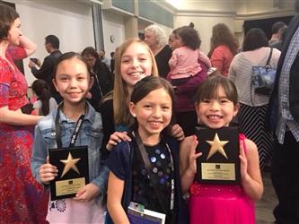 students smiling and holding up plaques