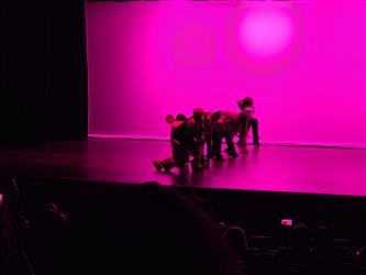 dancers in line backlit by pink background
